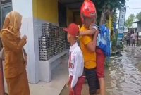 Suasana di depan SD Negeri 165726 Jalan Jenderal Sudirman, Kota Tebingtinggi, yang terendam banjir akibat meluapnya Sungai Padang. Terlihat para siswa sedang dijemput dan dievakuasi oleh orang tua atau warga karena kegiatan belajar mengajar terpaksa diliburkan demi keselamatan. Foto: Ist.