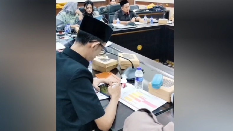 Achmad Syahri Assidiqi, anggota DPRD Jember dari Partai Gerindra, terlihat asyik menunduk memainkan ponsel diduga bermain gim sambil merokok di meja sidang saat rapat Komisi D bersama Dinas Kesehatan membahas penanganan stunting. Foto: Ist.