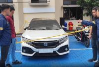Petugas kepolisian melakukan pemeriksaan dan pengamanan terhadap mobil Honda Civic Turbo warna putih milik Kepala Desa Purwasaba (Kades Hoho) yang dibakar di Kabupaten Banjarnegara. Foto: Ist.