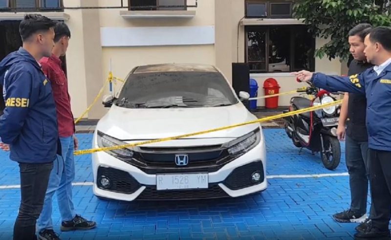 Petugas kepolisian melakukan pemeriksaan dan pengamanan terhadap mobil Honda Civic Turbo warna putih milik Kepala Desa Purwasaba (Kades Hoho) yang dibakar di Kabupaten Banjarnegara. Foto: Ist.