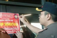 Petugas Satuan Polisi Pamong Praja (Satpol PP) Kabupaten Karawang memasang stiker pemberitahuan penutupan sementara pada lokasi Karawang Theatre Night Mart, Selasa (9/6/2026). Foto: Ist.