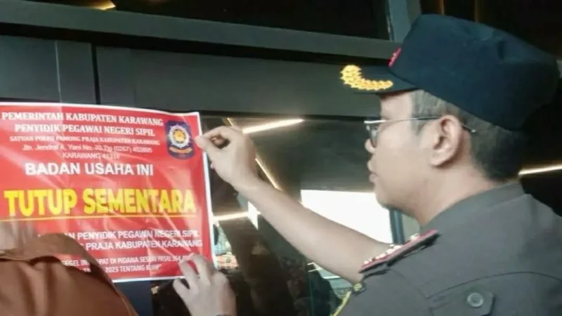 Petugas Satuan Polisi Pamong Praja (Satpol PP) Kabupaten Karawang memasang stiker pemberitahuan penutupan sementara pada lokasi Karawang Theatre Night Mart, Selasa (9/6/2026). Foto: Ist.