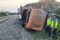 Kondisi truk Mitsubishi yang hancur dan terbalik di samping rel kereta api setelah ditabrak KA Putri Deli di pelintasan sebidang tanpa palang pengaman di Perbaungan, Serdang Bedagai, Minggu (2/8/2026). Kecelakaan itu menewaskan sopir truk dan menyebabkan lokomotif kereta sempat anjlok keluar jalur. Foto: Ist.