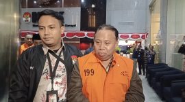 Rektor Universitas Jenderal Soedirman, Akhmad Sodiq, mengenakan rompi oranye tahanan KPK saat digiring petugas menuju mobil tahanan di Gedung Merah Putih KPK, Jakarta, Sabtu (22/8/2026). Foto: Ist.