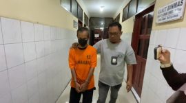 Tersangka Mudasir, Sekretaris Dinas Peternakan Labuhanbatu, didampingi petugas kepolisian setelah ditangkap terkait dugaan penipuan bermodus proyek pengadaan laptop fiktif yang merugikan puluhan orang dengan kerugian mendekati Rp1 miliar. Foto: Ist.