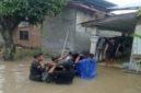 Sejumlah warga berusaha menyeberangkan dan menyelamatkan sepeda motor menerjang genangan banjir yang merendam pemukiman penduduk di Sumatera Utara. Foto: Ist.