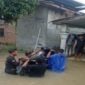 Sejumlah warga berusaha menyeberangkan dan menyelamatkan sepeda motor menerjang genangan banjir yang merendam pemukiman penduduk di Sumatera Utara. Foto: Ist.