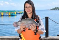 Friska Setiawani Saragih, Lake Manager Regal Springs Indonesia, menampilkan ikan tilapia hasil budidaya berkelanjutan di Danau Toba. Ia memimpin pengembangan varian KING Tilapia premium sekaligus menjaga standar kualitas air dan ekosistem agar produk Indonesia dapat bersaing di pasar global. Foto: Ist.