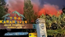 Kobaran api karhutla tampak menyala terang di balik papan penanda jalur pendakian Taman Wisata Alam Kawah Ijen, Sabtu (5/9/2026).