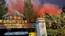 Kobaran api karhutla tampak menyala terang di balik papan penanda jalur pendakian Taman Wisata Alam Kawah Ijen, Sabtu (5/9/2026).