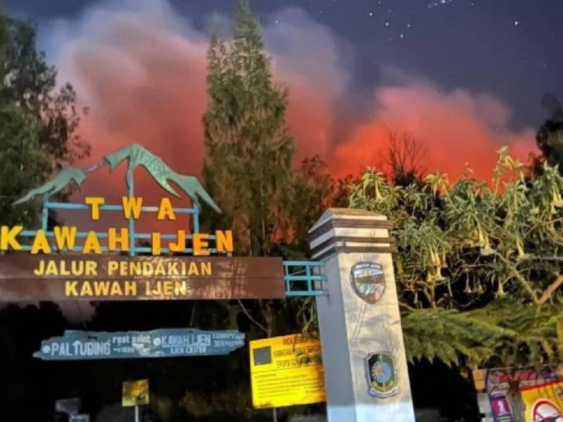 Kobaran api karhutla tampak menyala terang di balik papan penanda jalur pendakian Taman Wisata Alam Kawah Ijen, Sabtu (5/9/2026).